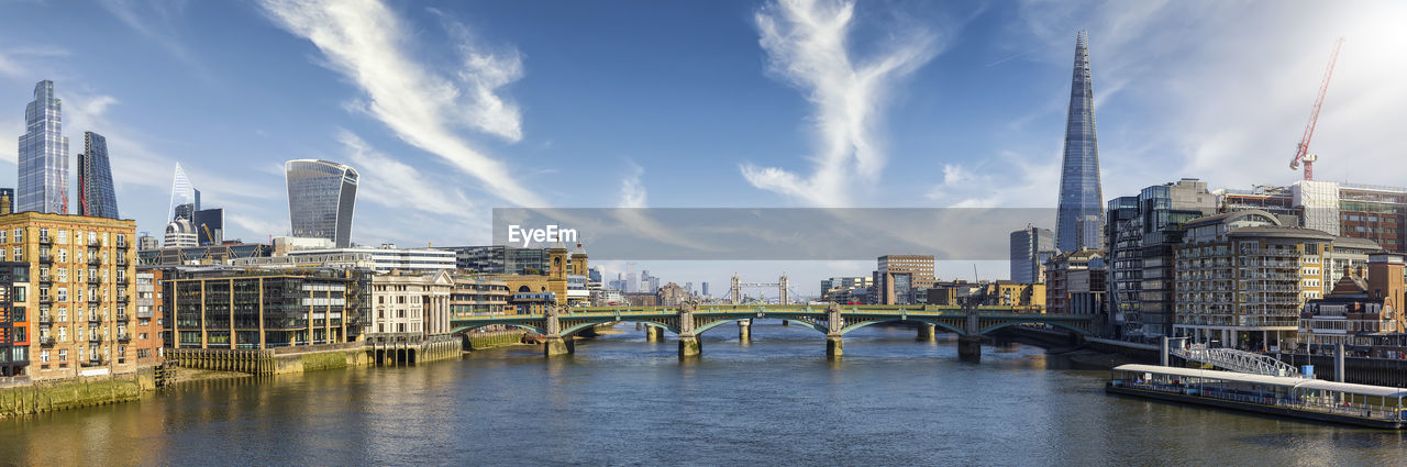 BRIDGE OVER RIVER BY BUILDINGS AGAINST SKY IN CITY