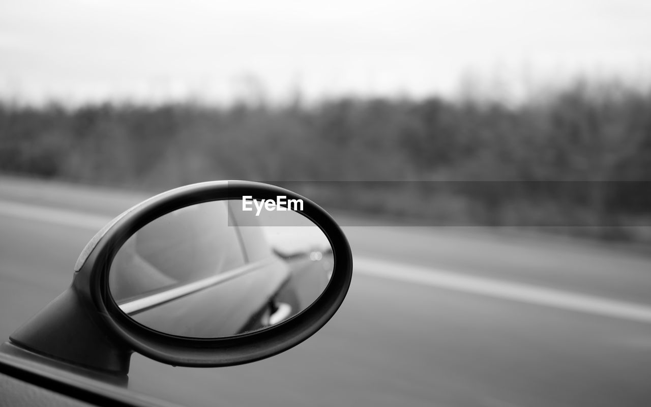 Black and white picture of an outer rear mirror driving along a field