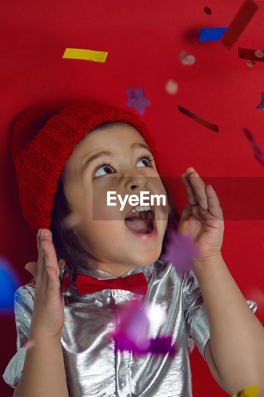 Christmas portrait of  boy child in silver shirt and red bow tie catches glitter confetti on holiday