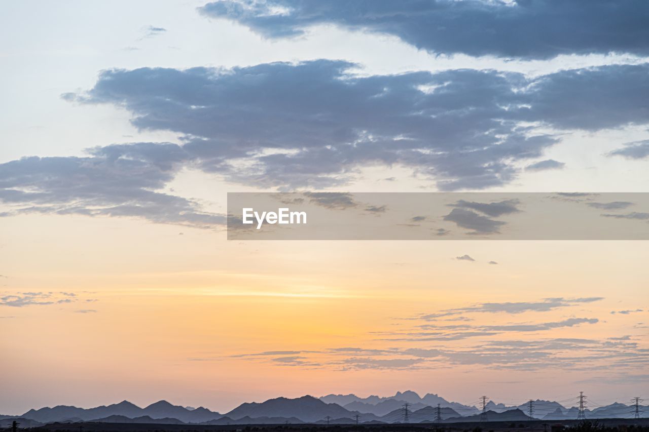 Scenic view of dramatic sky over silhouette mountains during sunset