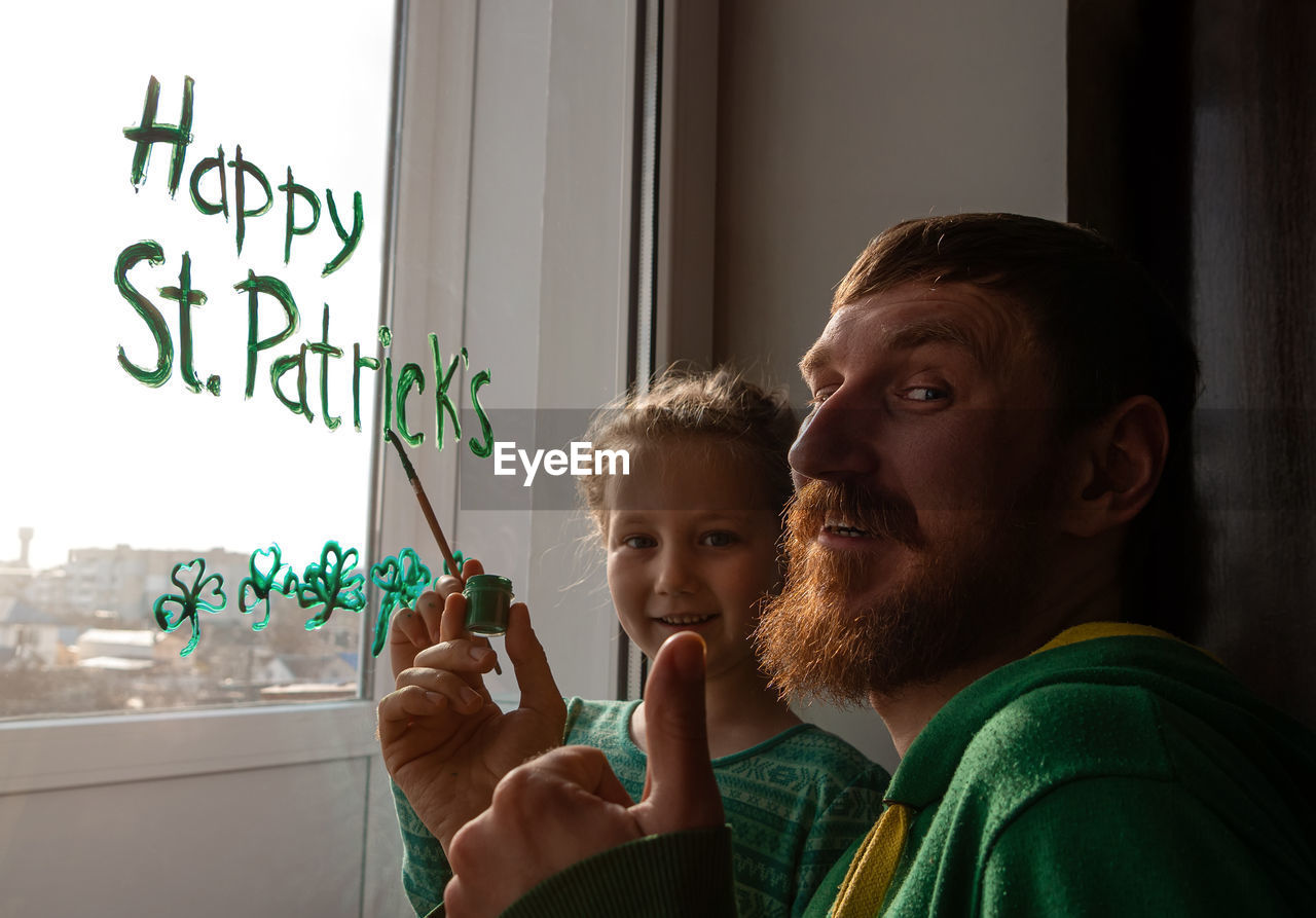 Drawing st. patrick's day father daughter painting green three-leaved shamrocks.stay home new normal