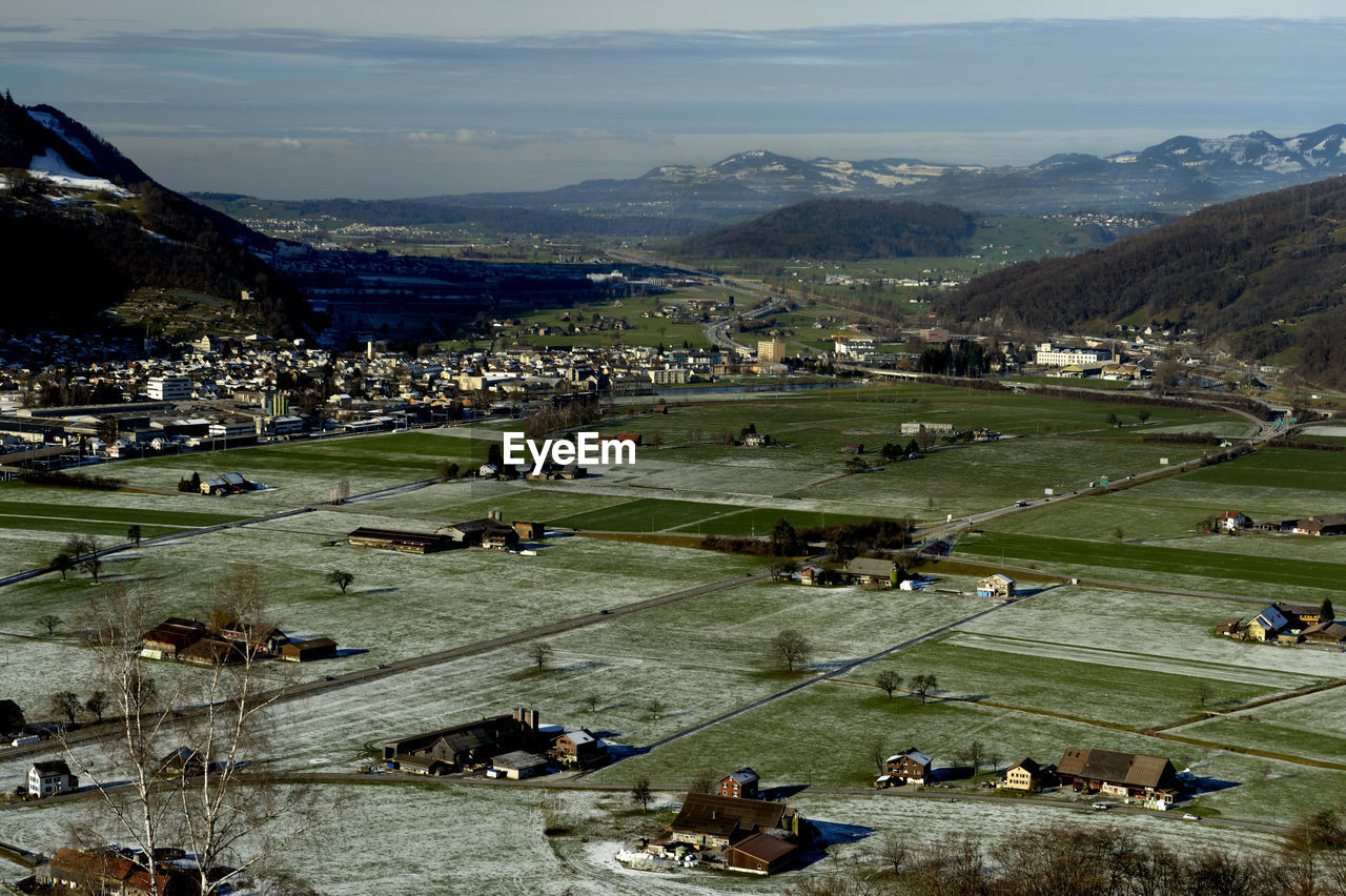 High angle view of buildings on field against mountains