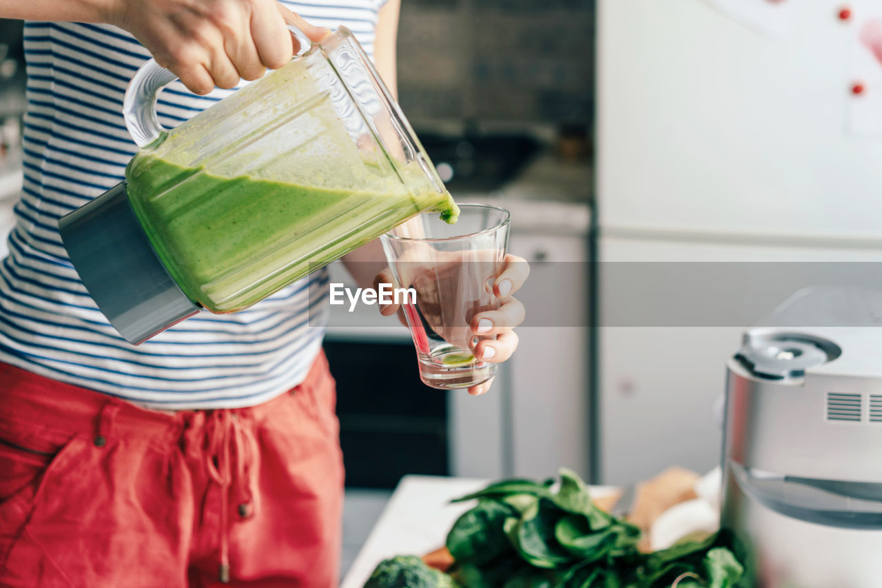 Midsection of woman pouring juice in glass