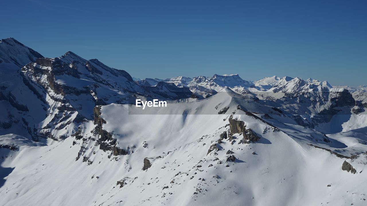 Scenic view of snowcapped mountains against clear blue sky