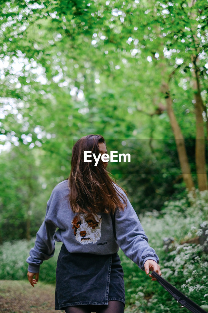 YOUNG WOMAN STANDING ON TREE