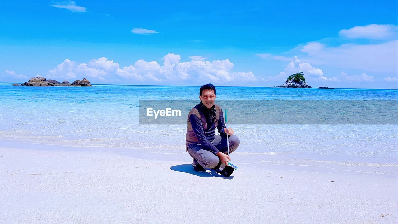 Full length of woman sitting on beach against sky