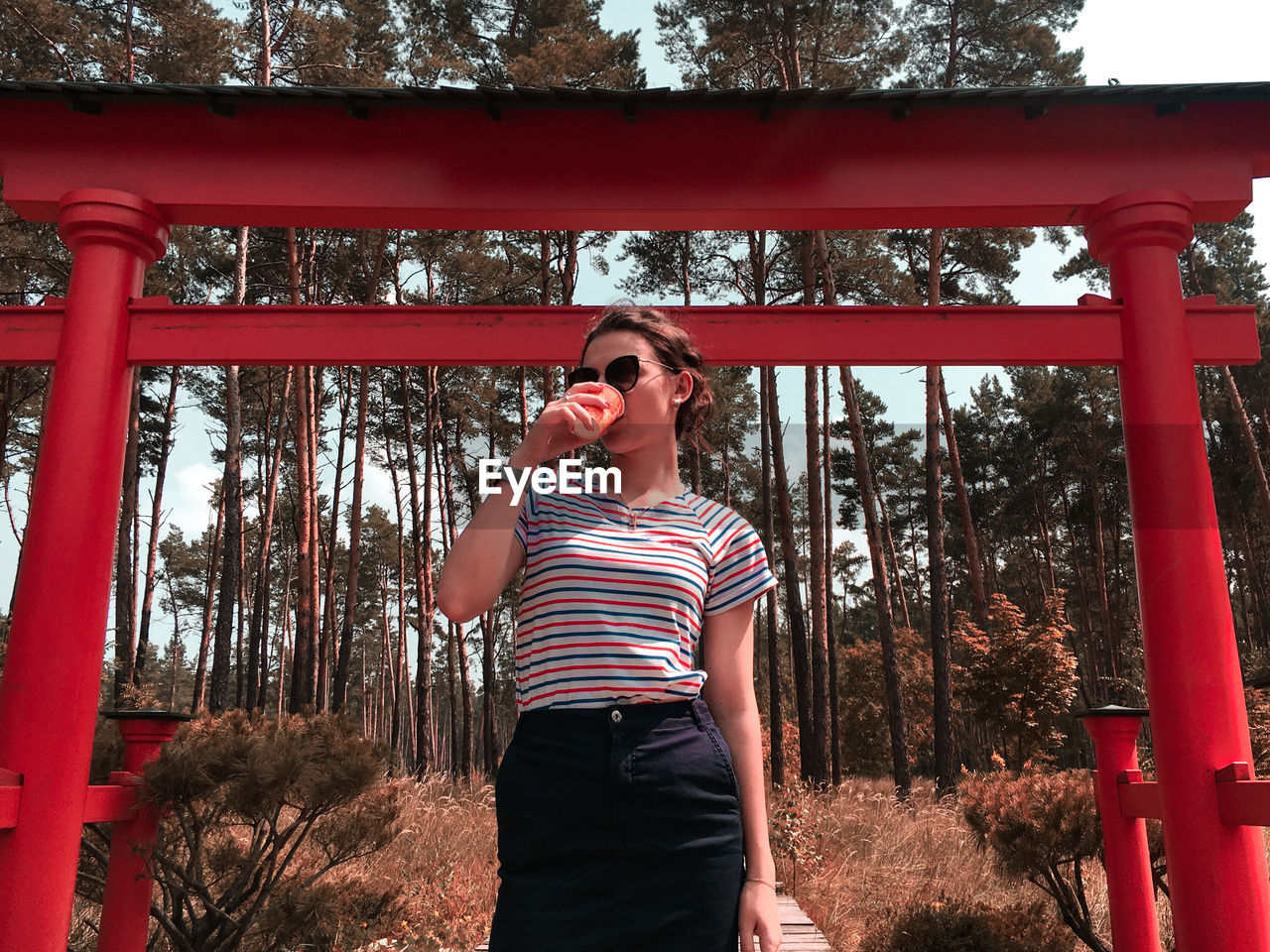 YOUNG WOMAN WEARING SUNGLASSES STANDING BY TREES