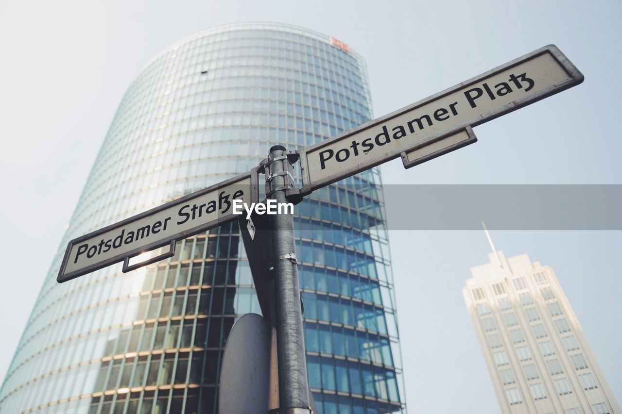 Low angle view of information sign and buildings against clear sky