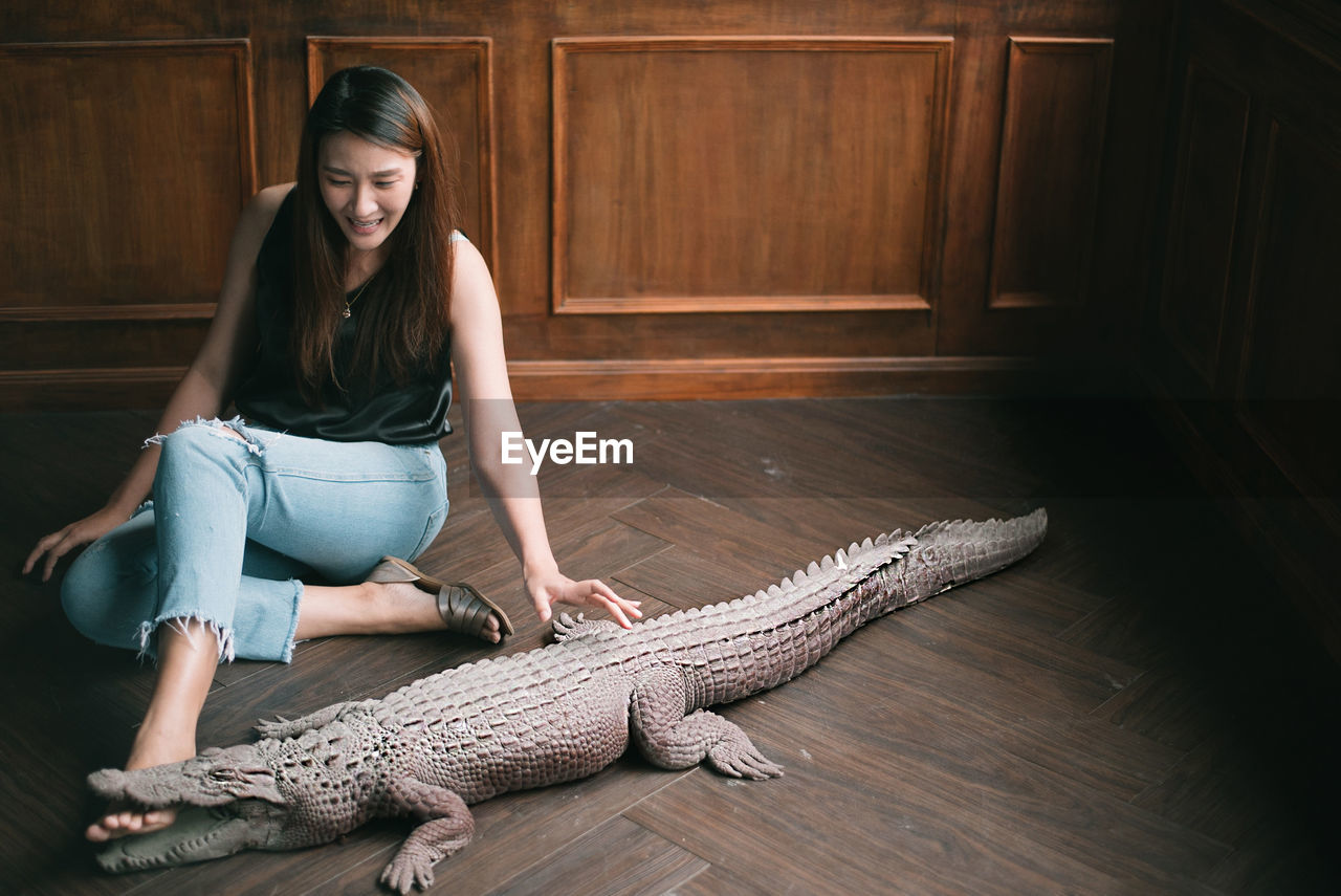 Young woman sitting by crocodile statue on floor