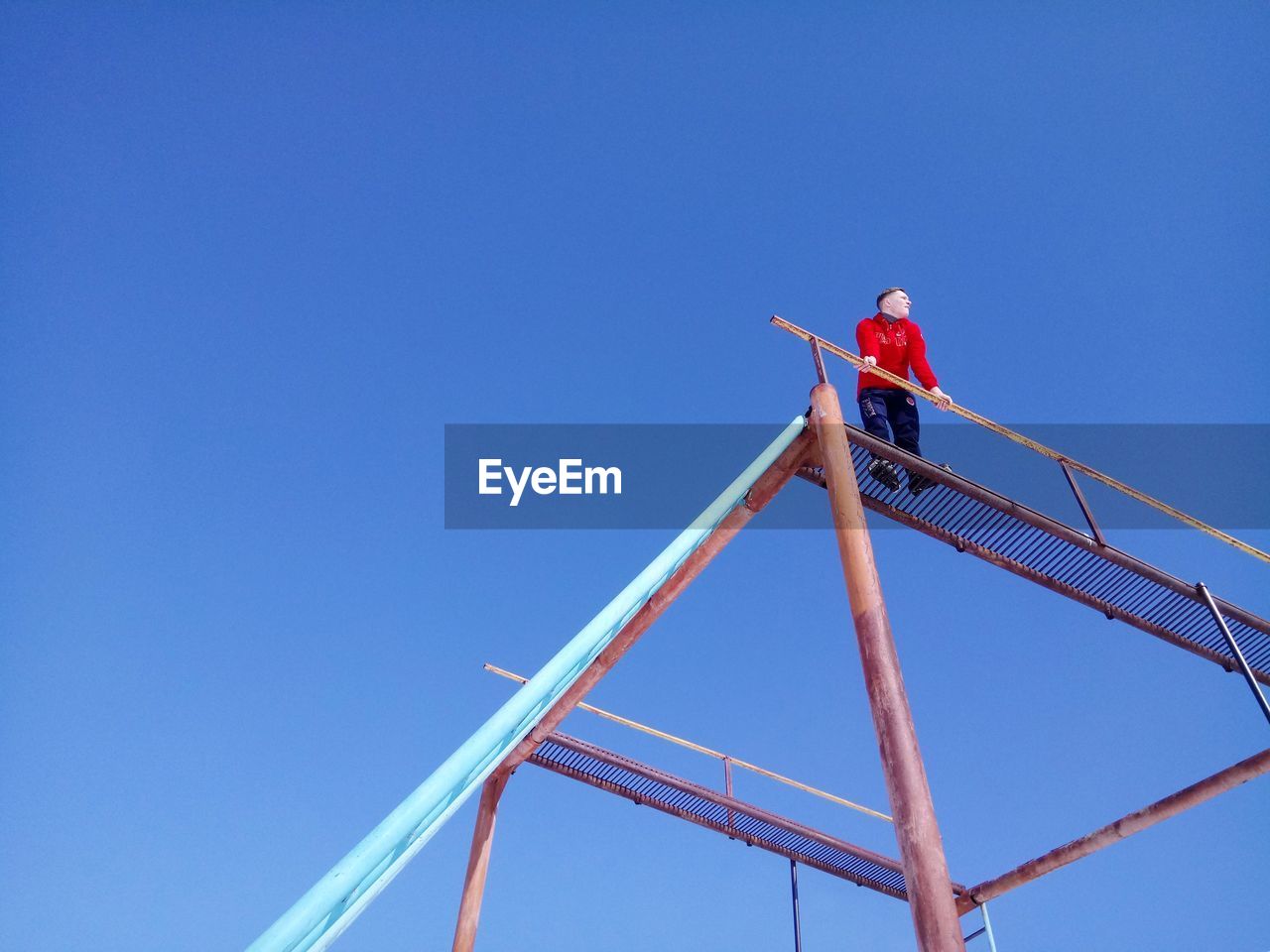 LOW ANGLE VIEW OF MAN WORKING ON CONSTRUCTION SITE AGAINST SKY