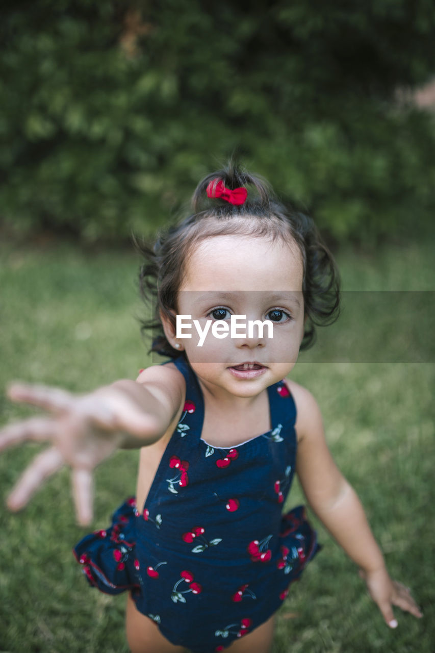 Cute baby girl gesturing while standing on grassy land in park