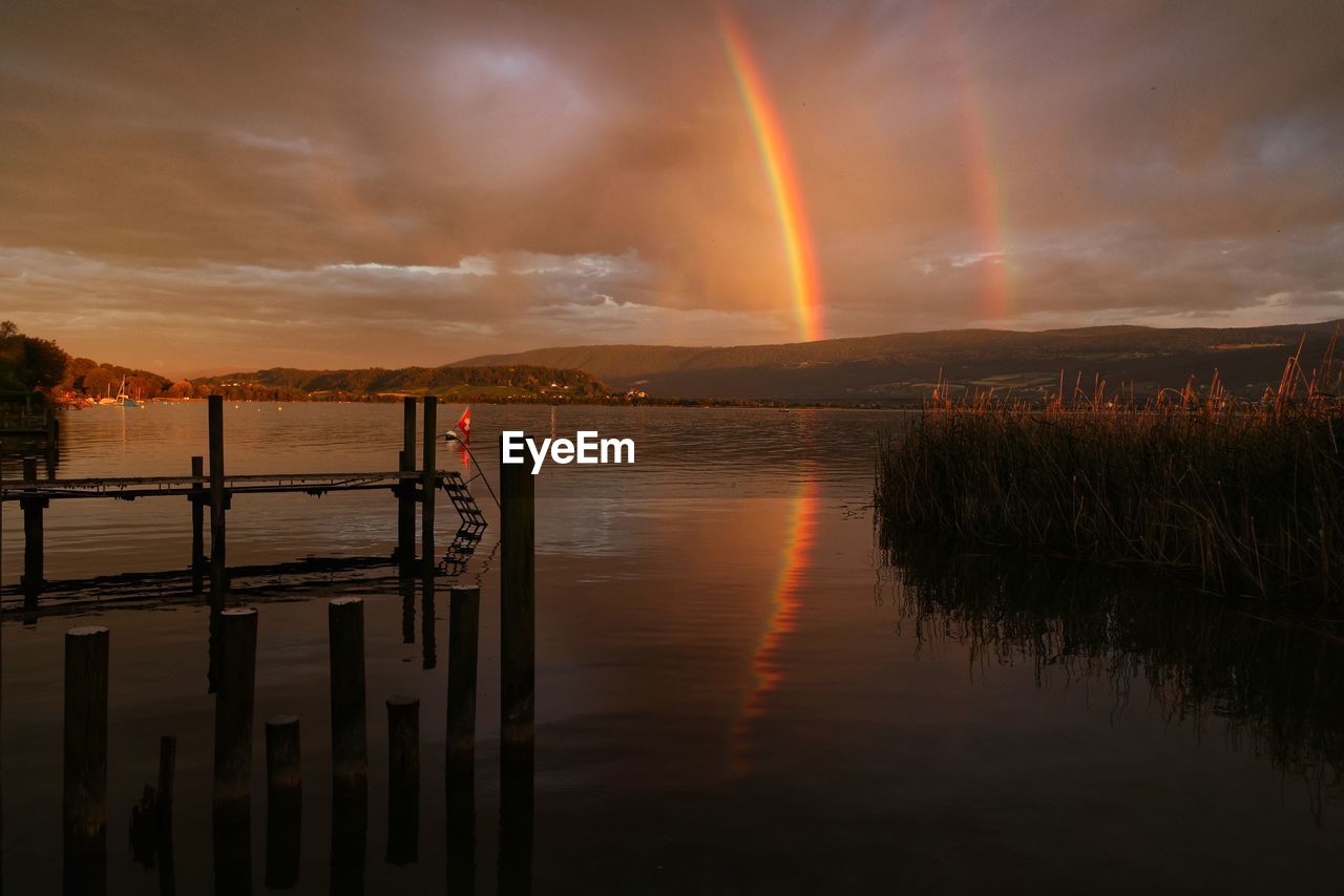Scenic view of a double rainbow over lake against sky during sunrise