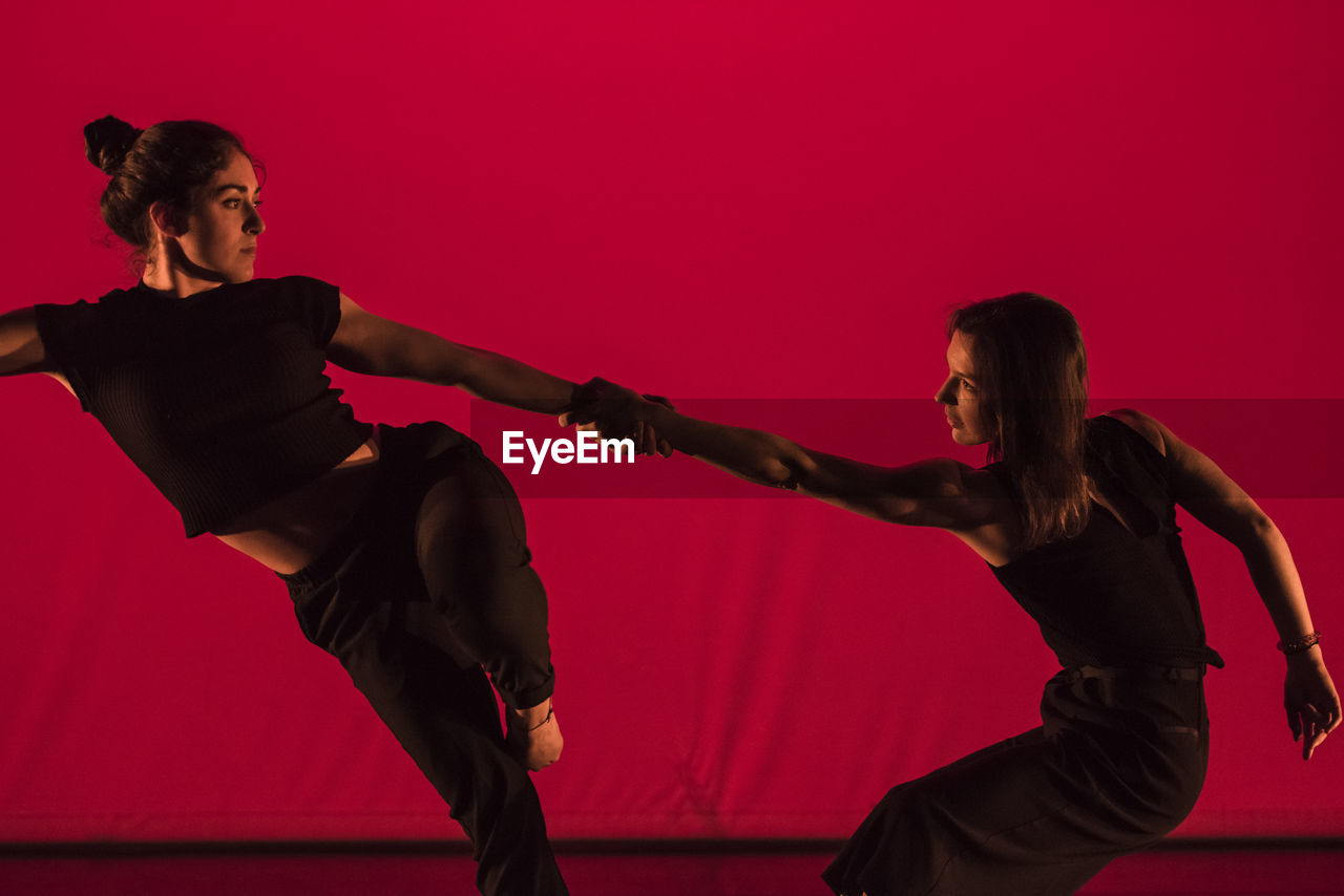 Young women dancing against red background