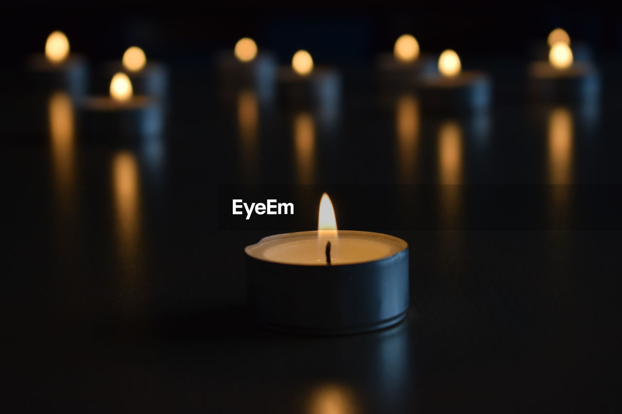 Close-up of illuminated candles on table in darkroom