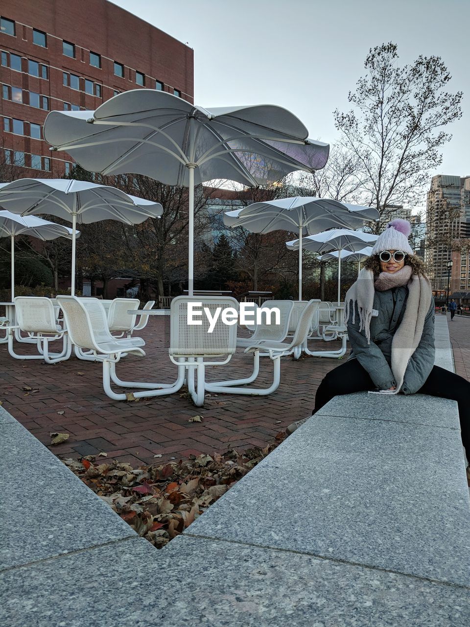 WOMAN SITTING AGAINST BUILDING