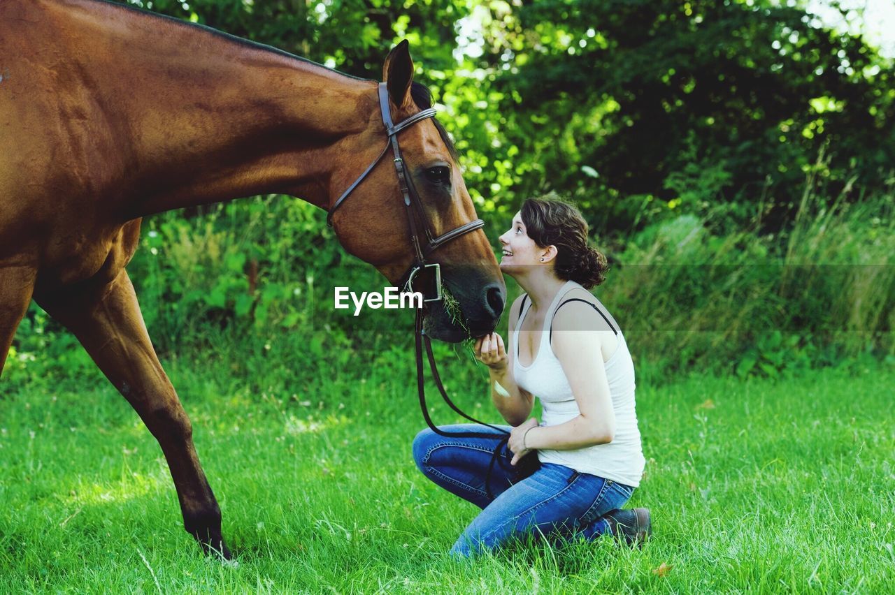 Side view of woman looking at horse on field