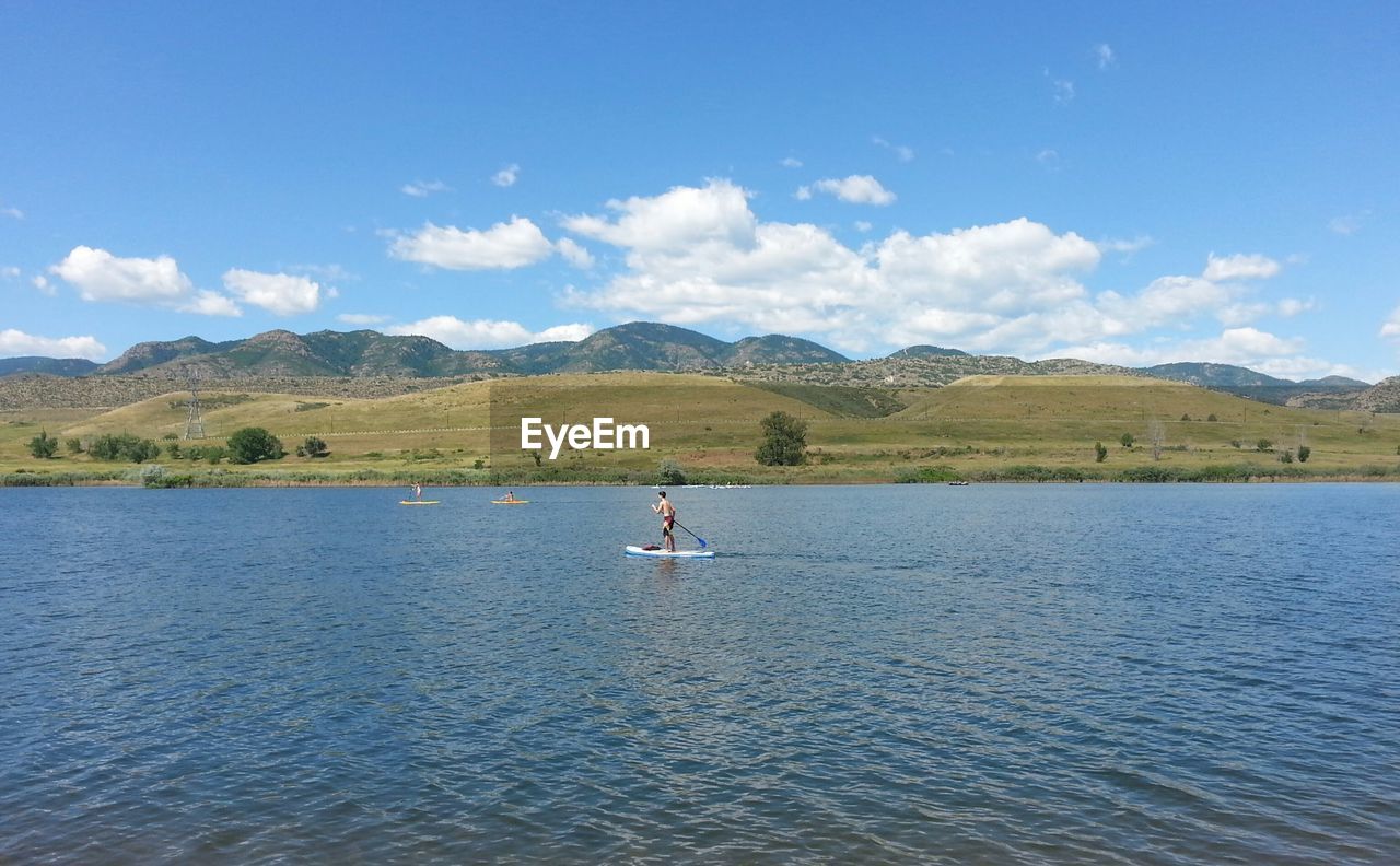 MAN SURFING IN LAKE AGAINST SKY