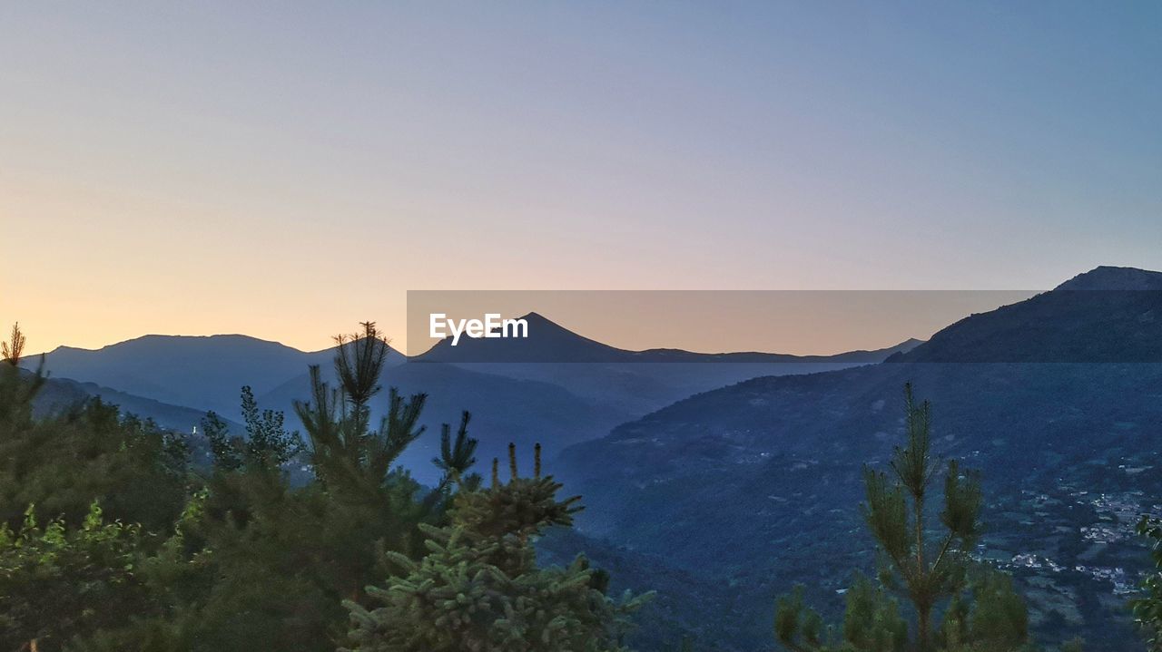 mountain, scenics - nature, sky, environment, landscape, beauty in nature, wilderness, mountain range, nature, tree, plant, sunset, land, travel, ridge, tranquility, travel destinations, forest, tranquil scene, no people, mountain peak, non-urban scene, coniferous tree, pinaceae, outdoors, tourism, twilight, pine tree, clear sky, blue, valley, plateau, summit, sun, idyllic, leisure activity, dawn, silhouette, cloud, activity, sunlight, pine woodland, copy space