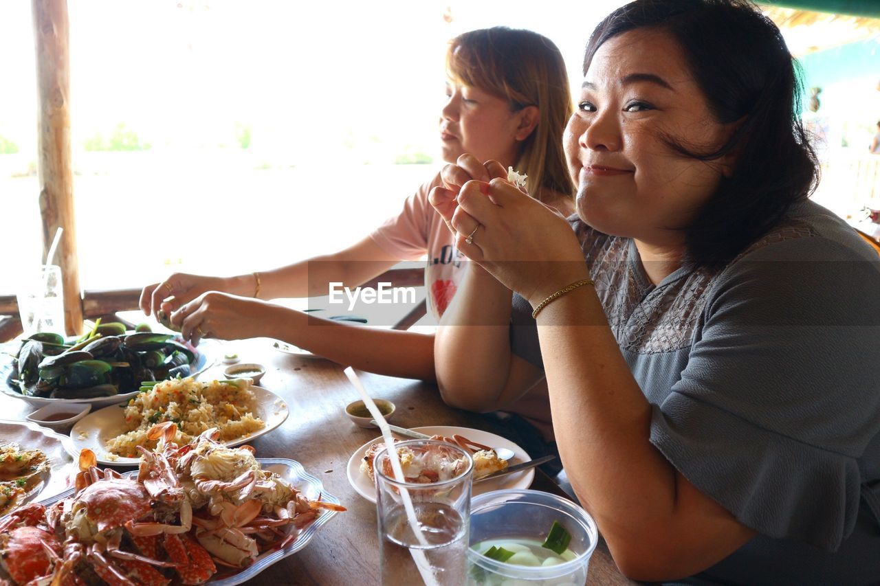 Portrait of smiling woman having food with friend at restaurant