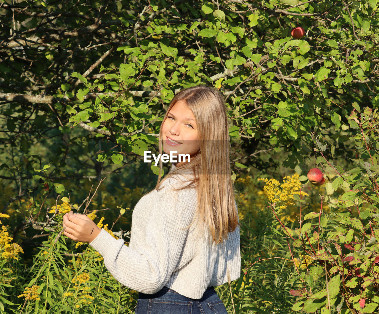 Portrait of smiling young woman against plants