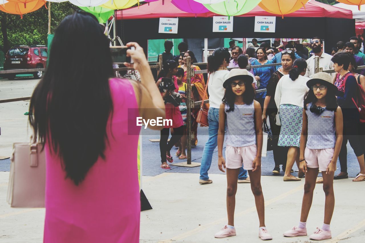 Rear view of mother photographing twin daughters