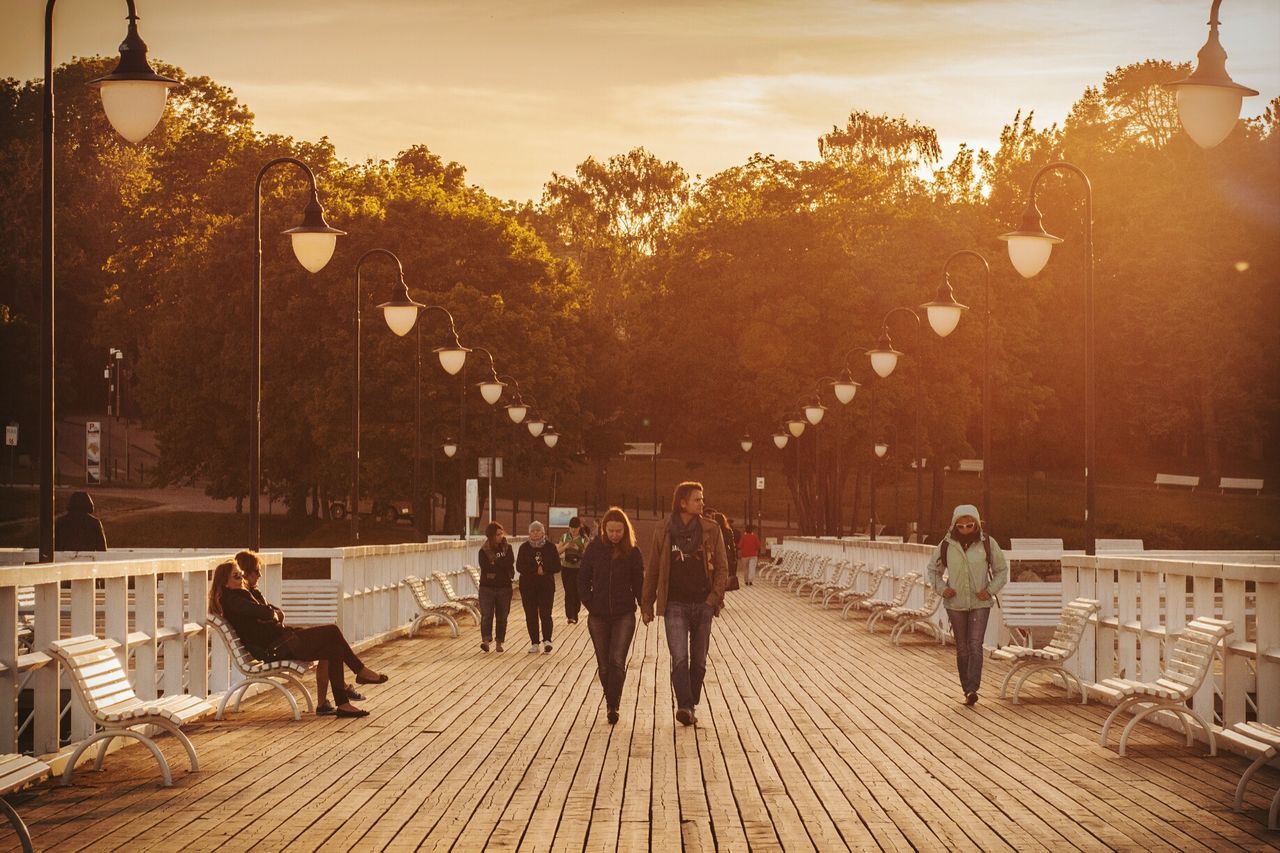 PEOPLE SITTING IN PARK AGAINST SKY