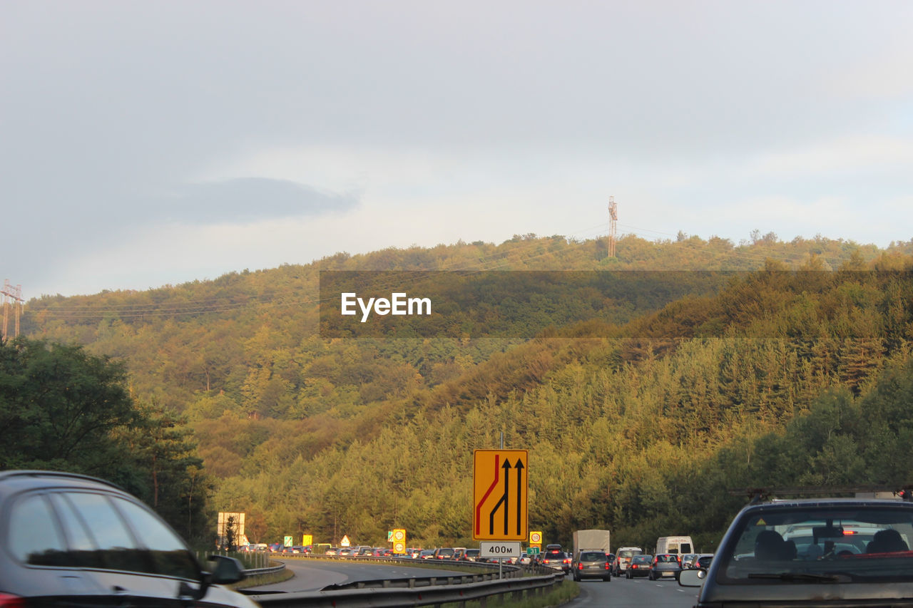 Cars on road against cloudy sky