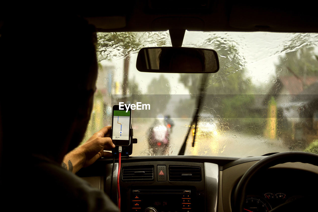 Man using navigation map on mobile phone while sitting in car