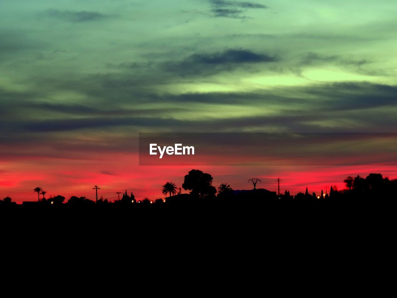 Silhouette landscape against cloudy sky during sunset