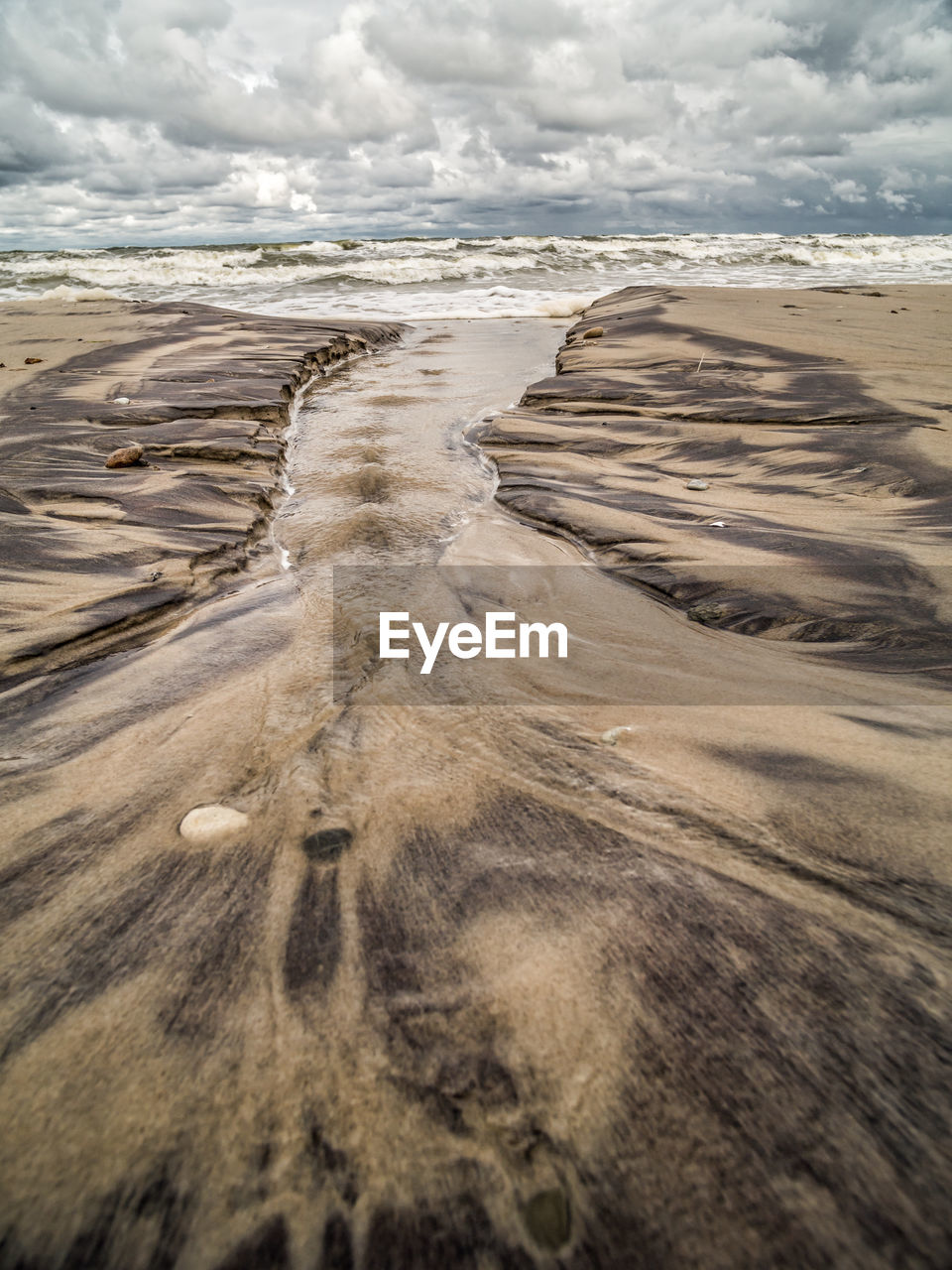 Tidal watercourse and marks in wet sand on the beach