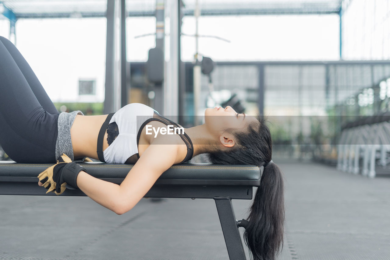 Young woman exercising on bench at gym