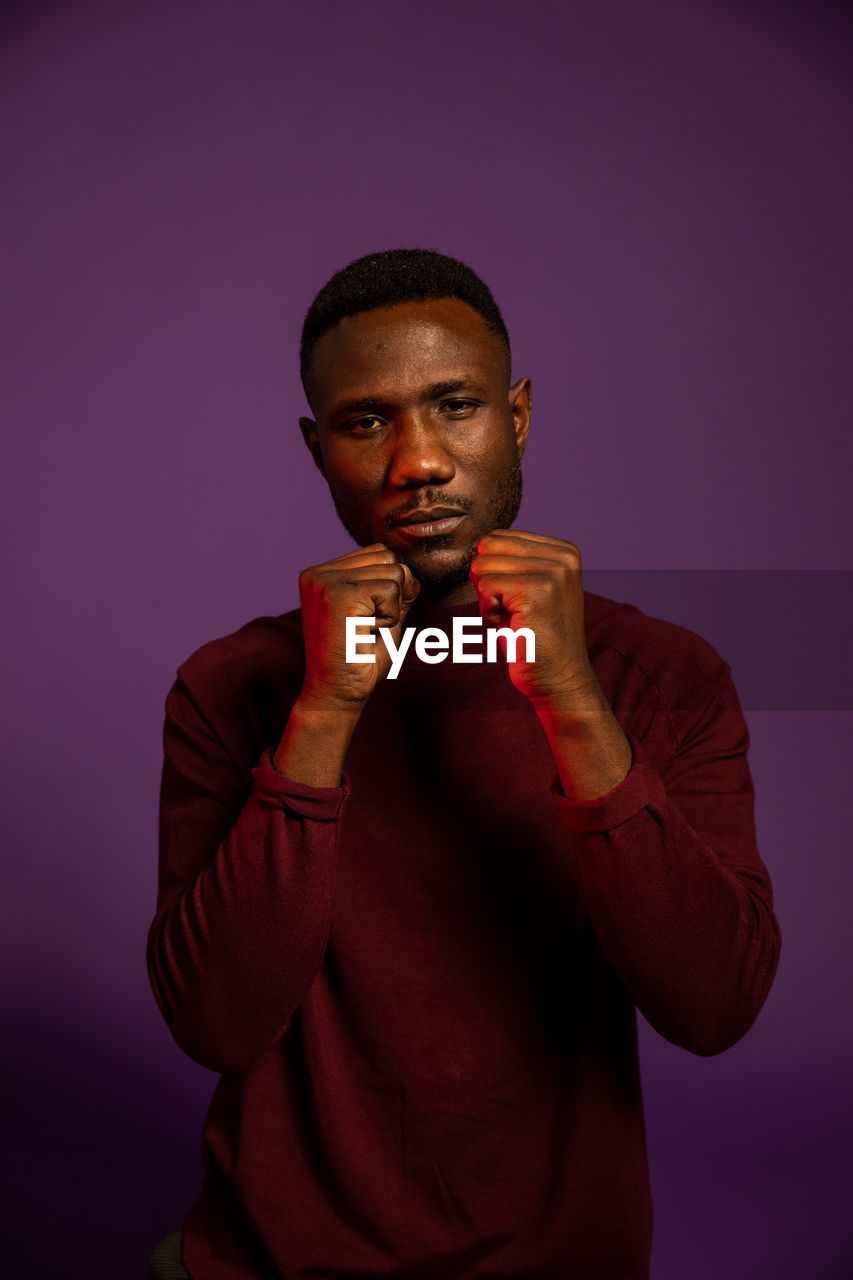 Portrait of young man standing against colored background