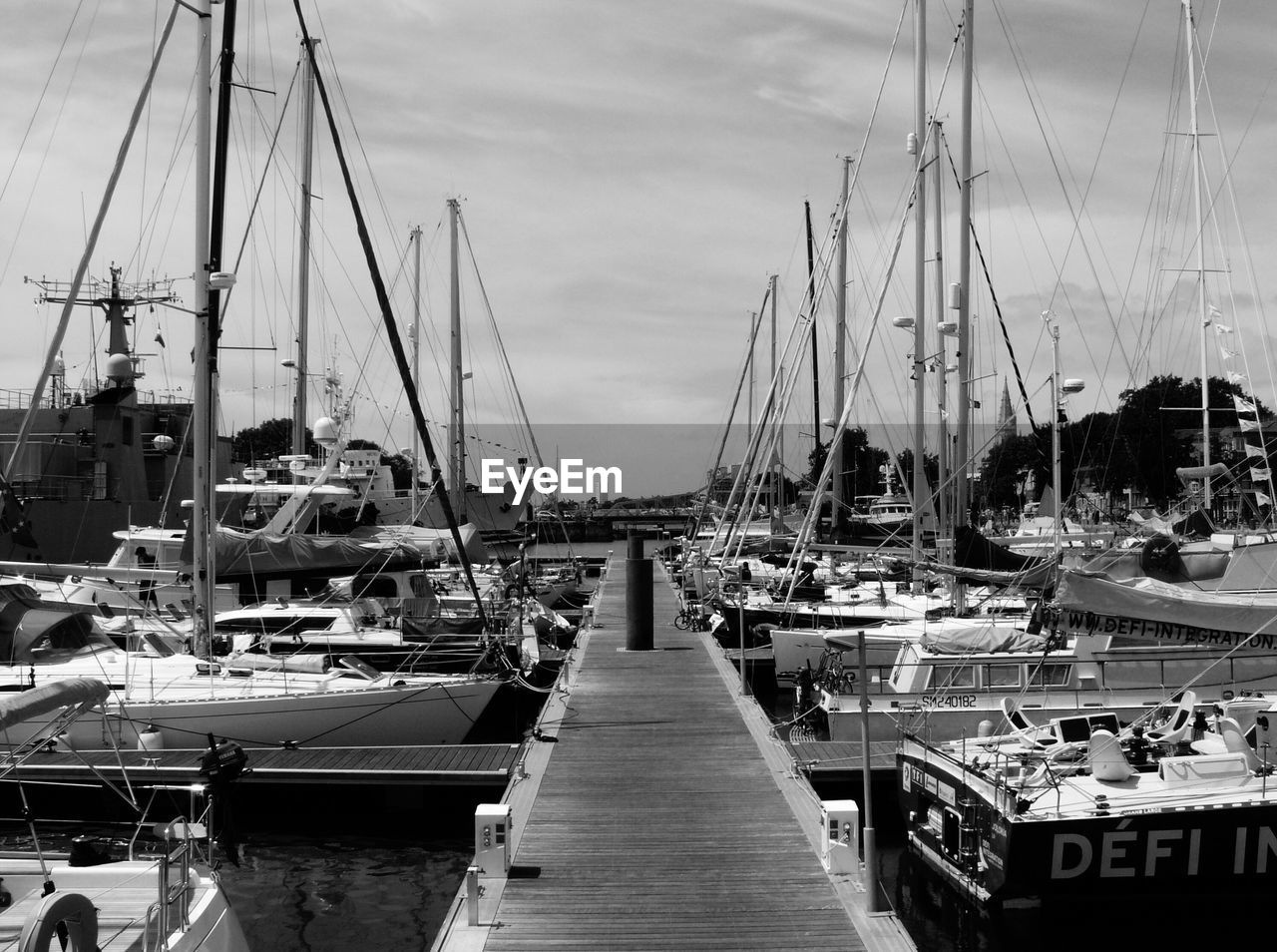 SAILBOATS MOORED AT HARBOR AGAINST SKY