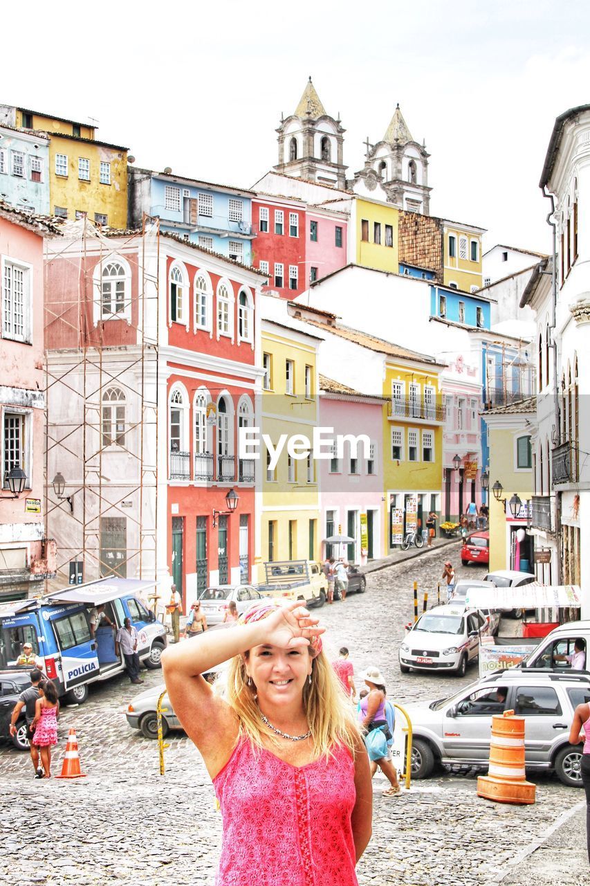 Portrait of smiling woman standing on street in city