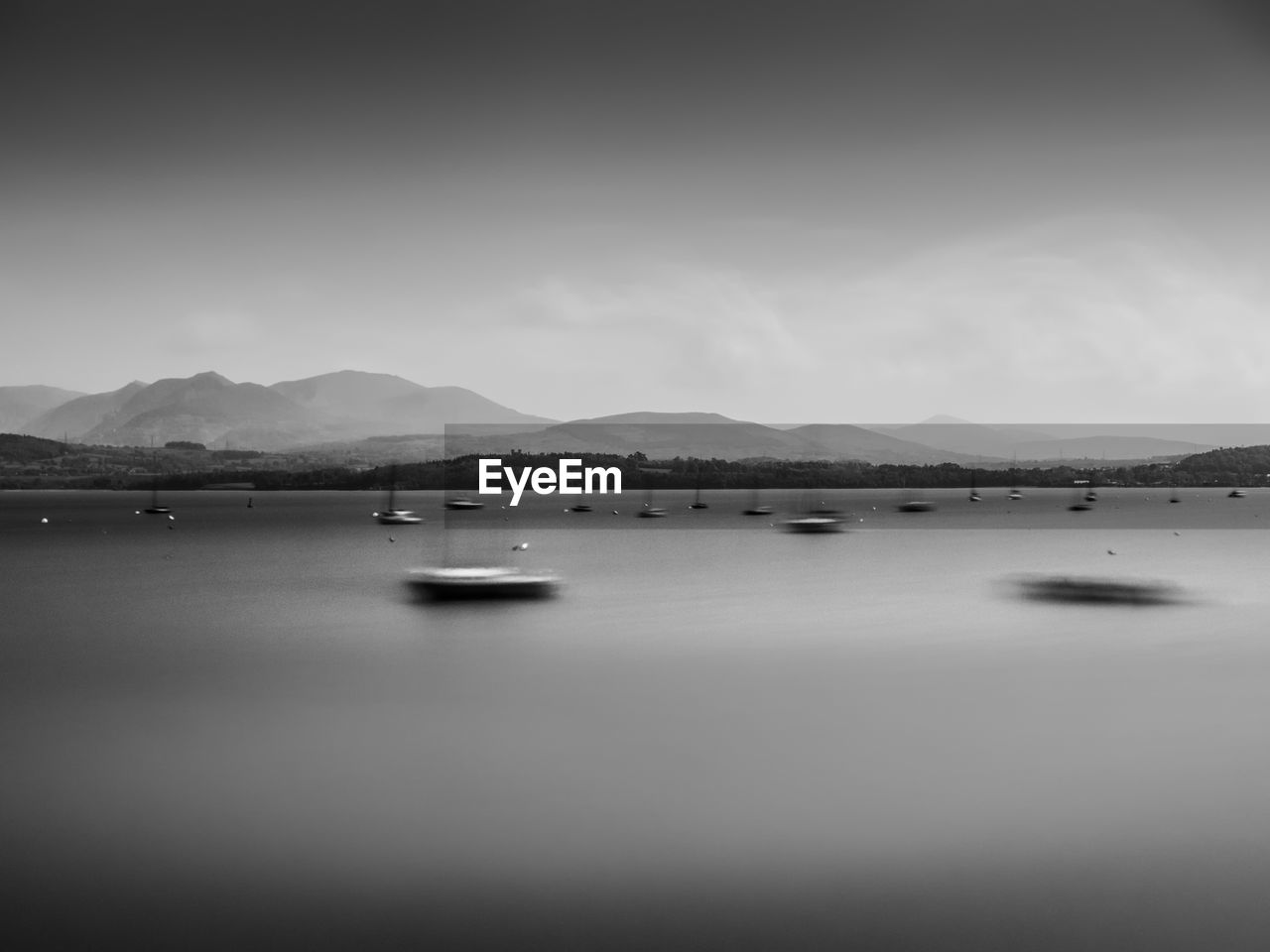 Blurred motion of boats in river against sky at dusk