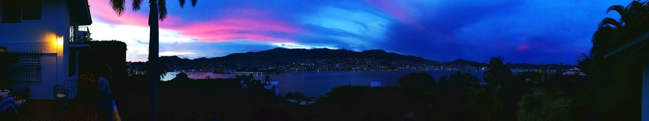 Panoramic view of illuminated city against sky at sunset