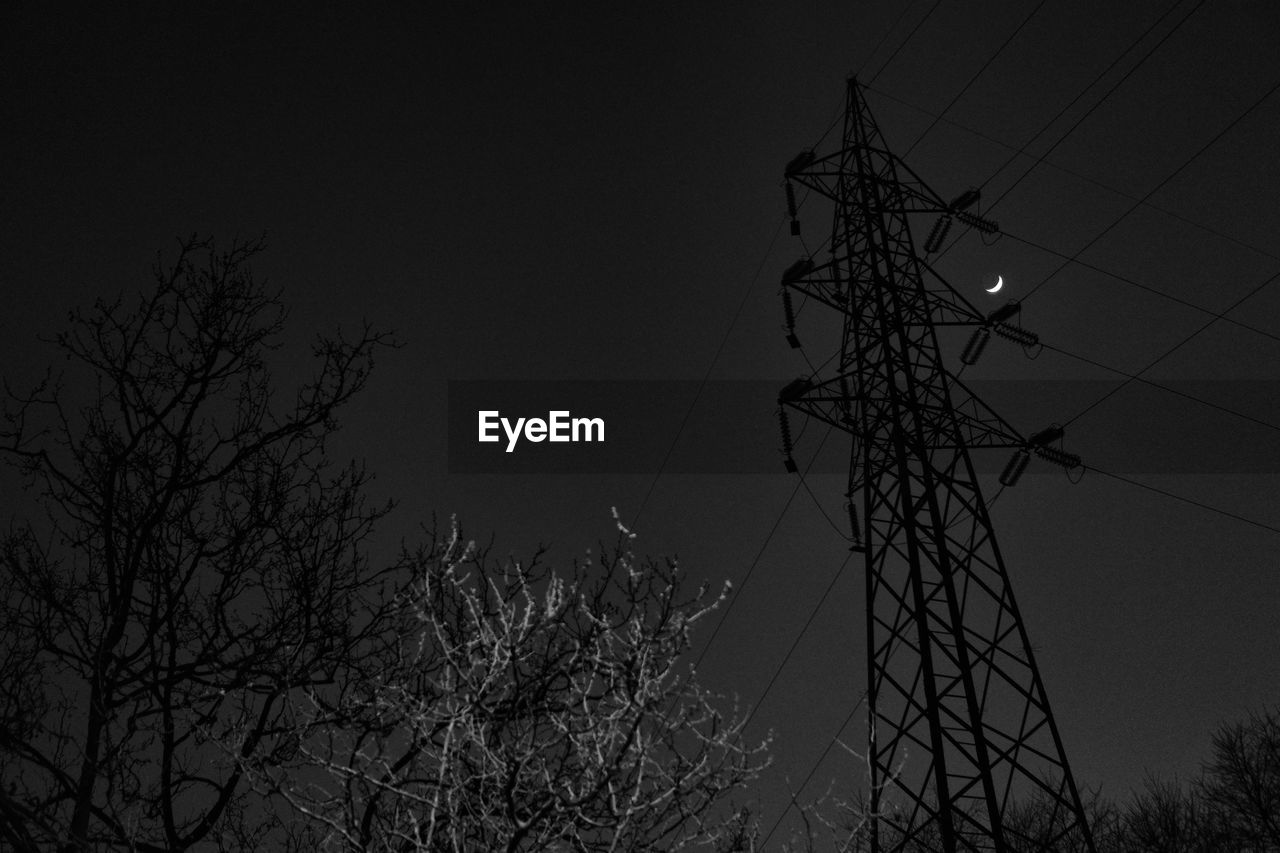 Low angle view of electricity pylon at night