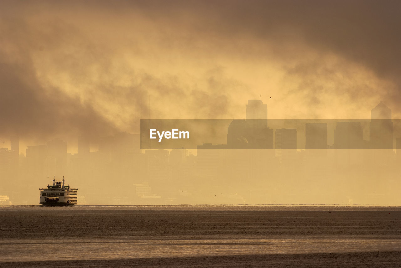 Ferry boat in sea against skyline during sunset