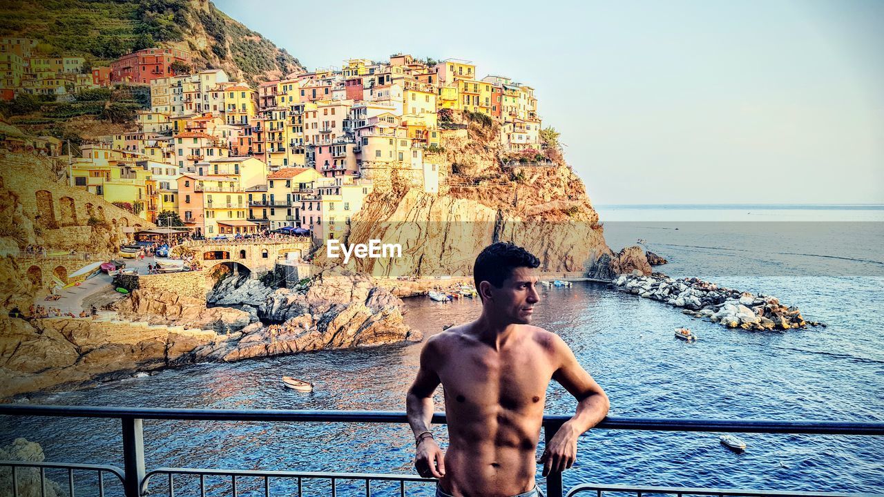 Shirtless man standing against sea at cinque terre