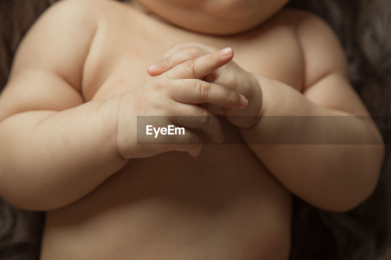 Midsection of shirtless baby boy lying on bed