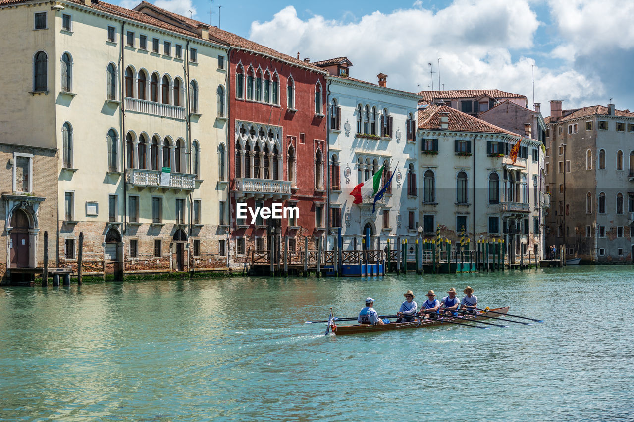 People rowing boat in grand canal against buildings