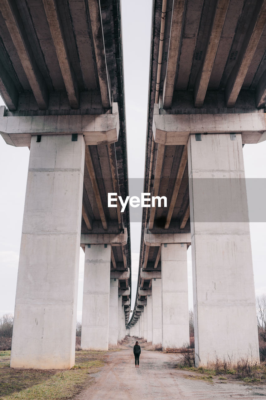 Full length of woman walking on road below bridge