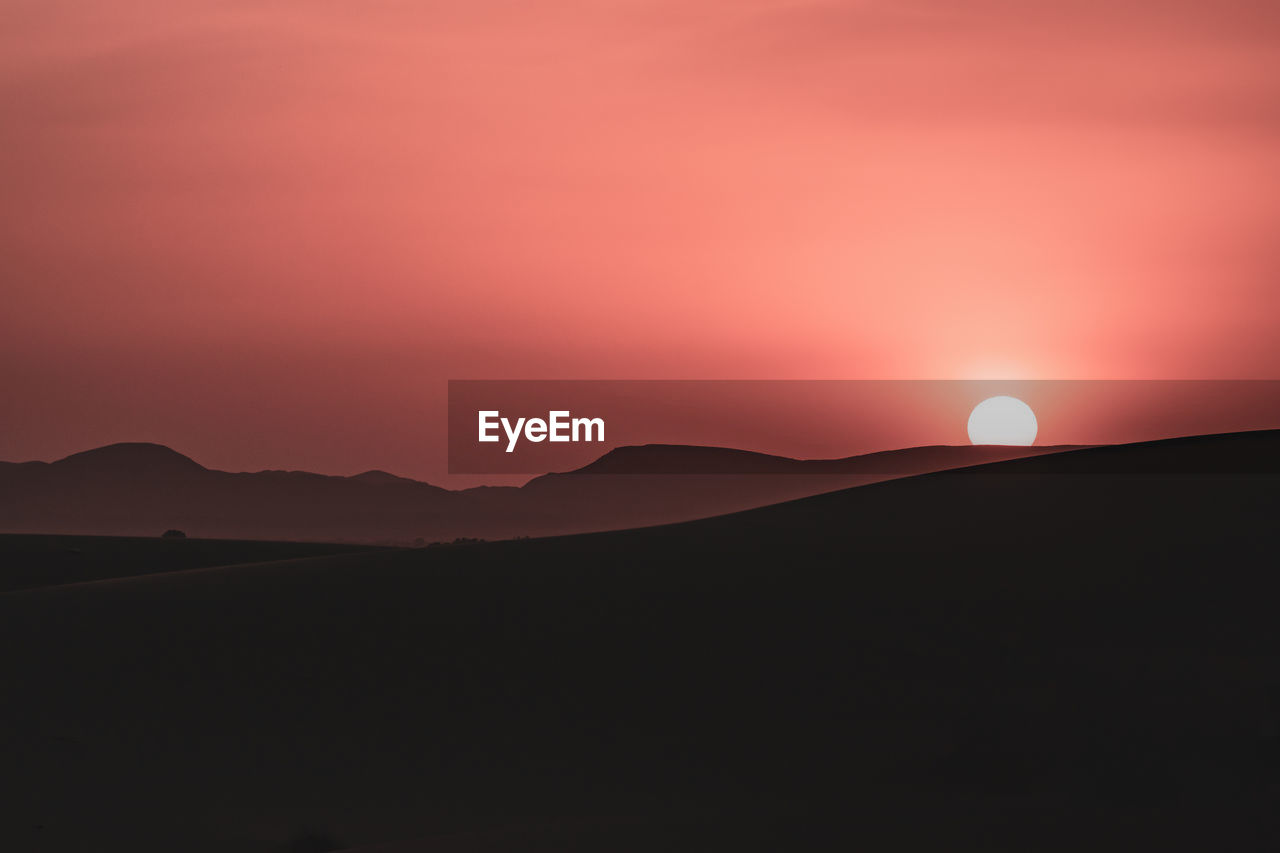 Scenic view of silhouette mountains against sky during sunset