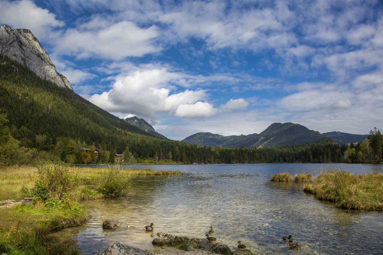 scenic view of lake by mountains against sky