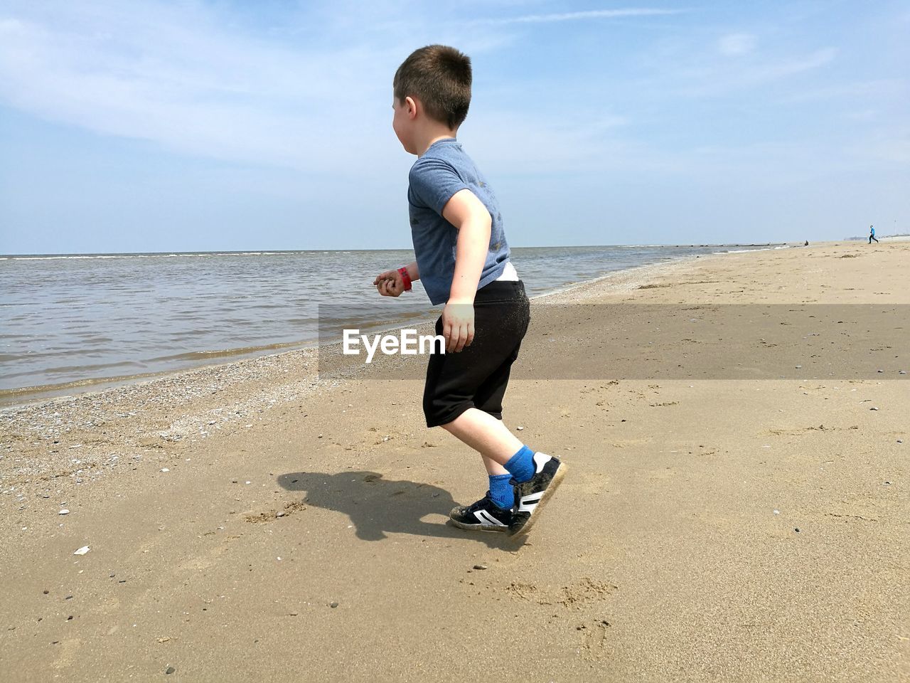 Full length of boy running at beach against sky