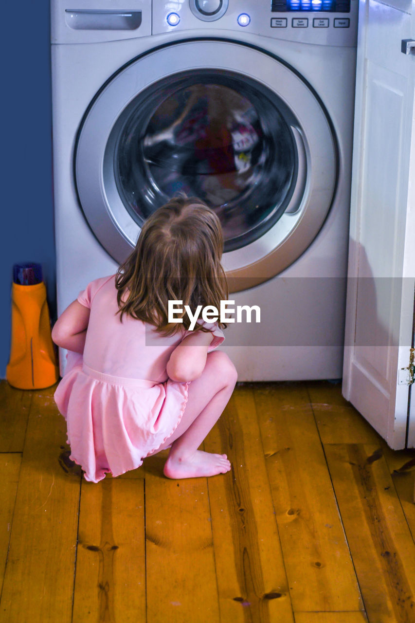 Little girl in pink anxiously watches as a machine cleans her favorite blanket