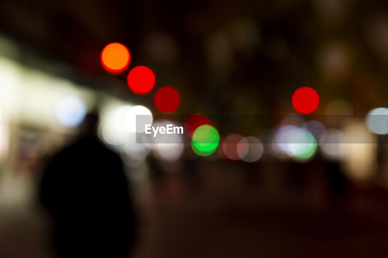 DEFOCUSED IMAGE OF ILLUMINATED LIGHTS ON STREET