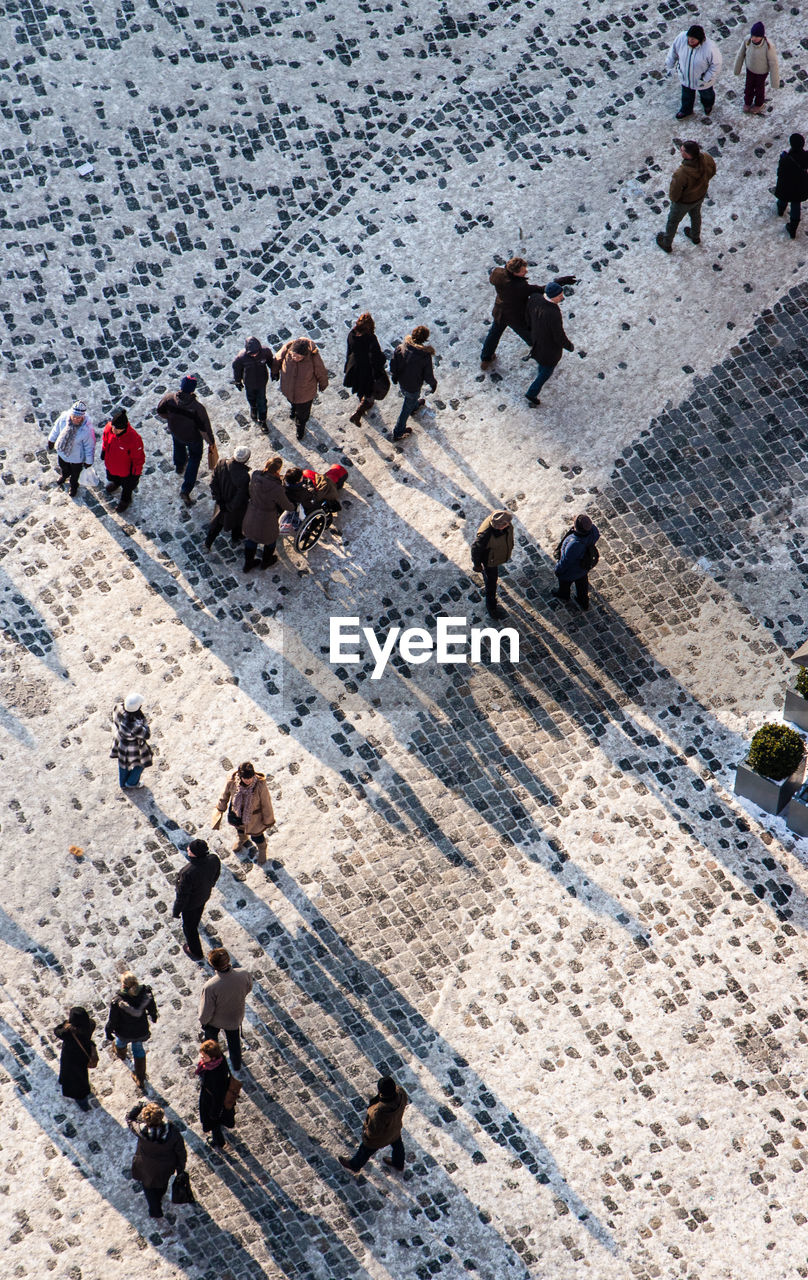 HIGH ANGLE VIEW OF GROUP OF PEOPLE WALKING ON ROAD