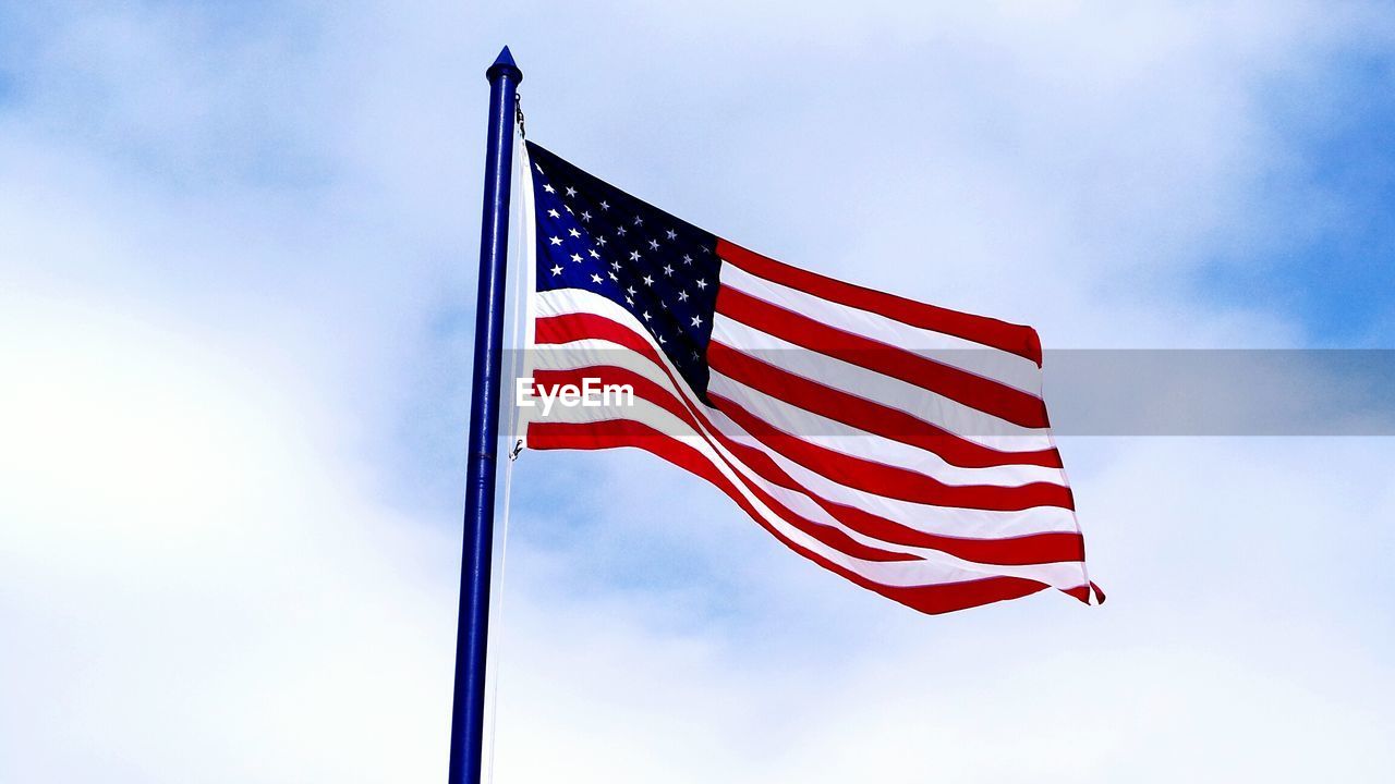 Low angle view of american flag against cloudy sky