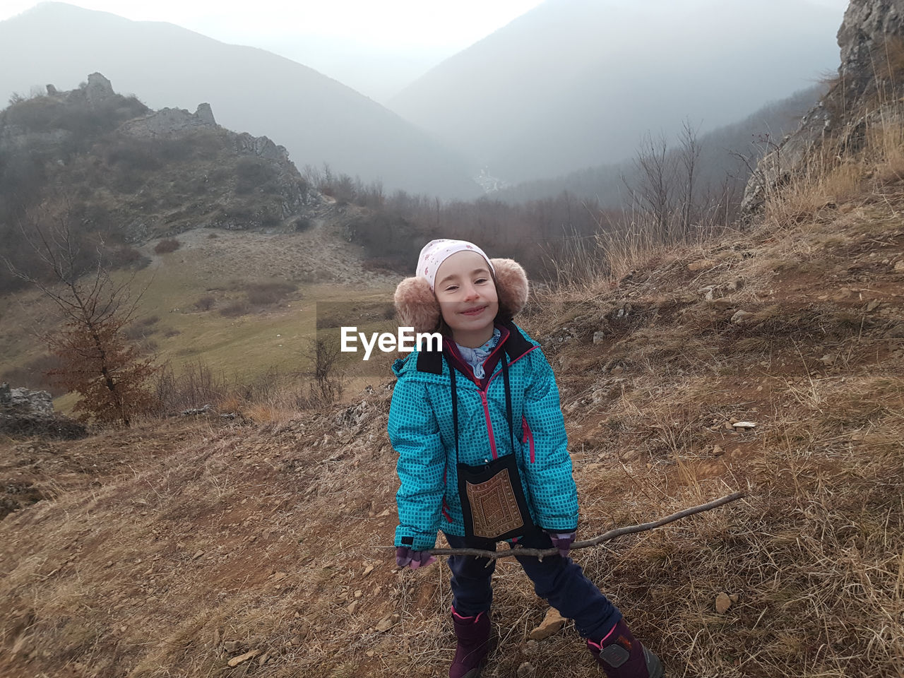 Cute young girl, kid posing with winter ear cap in the outdoors